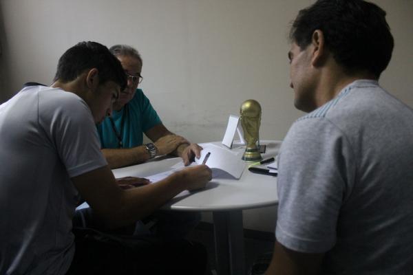 Andrey assinando o primeiro contrato profissional sob olhares do seu pai e Antnio Teixeira