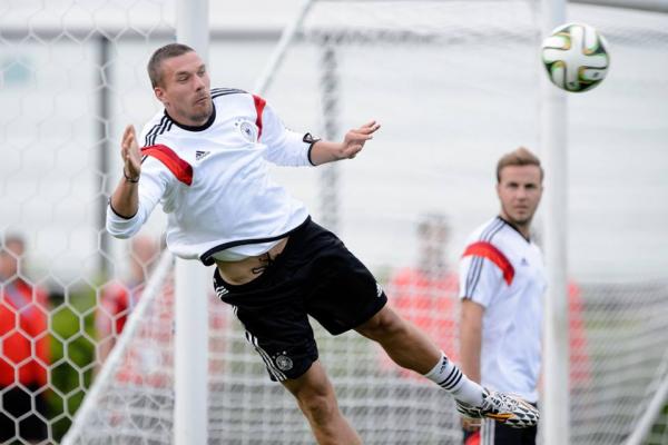 Atacante Podolski cabeceia bola e  observado pelo meia Gtze