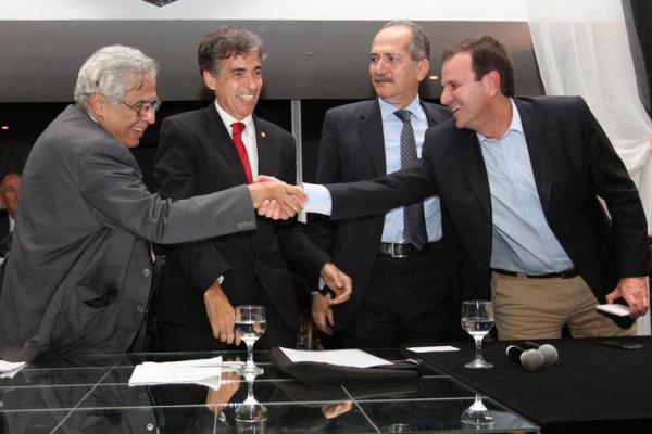 Sorridente, Eurico cumprimenta Paes ao lado de Luis Fernandes e Aldo Rebelo