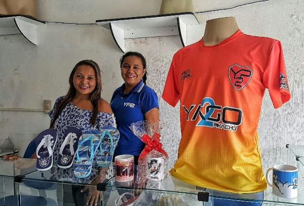 Vendedoras da loja oficial de Yago posam com caneca do Vasco e chinelos de Remo e Paysandu