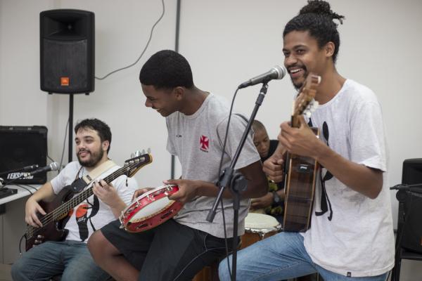 Zagueiro Eric Pimentel (centro) toca pandeiro ao lado do cantor Rodrigo Rios (dir)