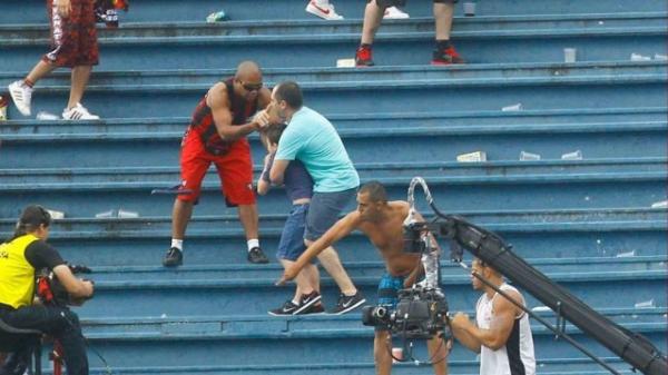 Segurando fortemente o filho, Joel Meneghelli ainda conversa e pega na mão de um dos torcedores do Atlético-PR