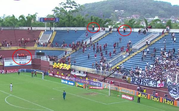Seguranas particulares de laranja observam a selvageria parados