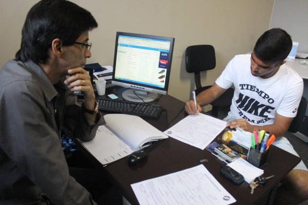Mauro Galvo observa Rafael Martins assinando contrato