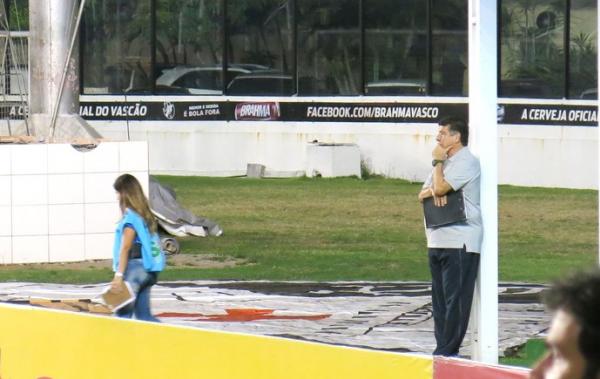 Contemplativo, o tcnico assiste ao jogo isolado e apoiado num poste
