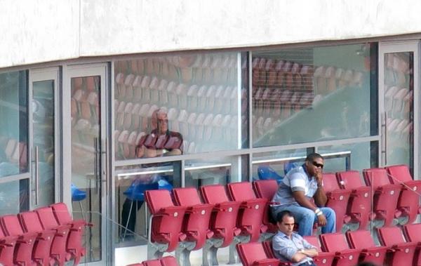 Dinamite assiste ao jogo escorado na parede do camarote. Do lado externo est Rodrigo Caetano