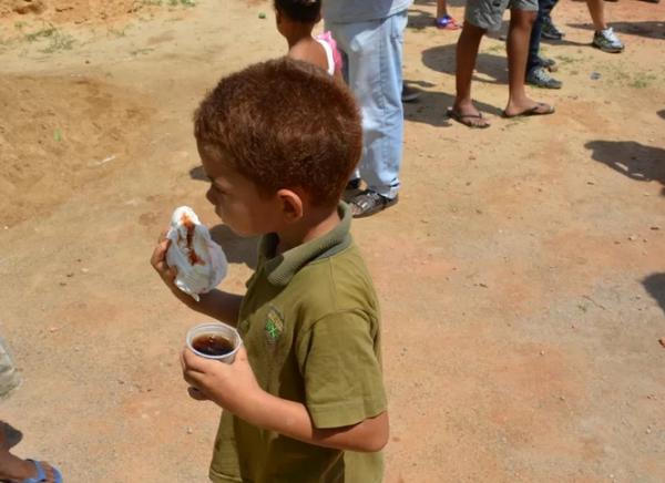 Garotinho saboreia cachorro-quente e refrigerante