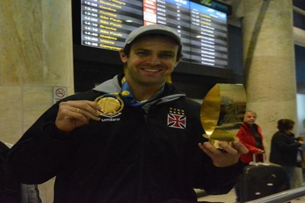 Gacho com o trofu de MVP e a medalha de ouro no embarque do time