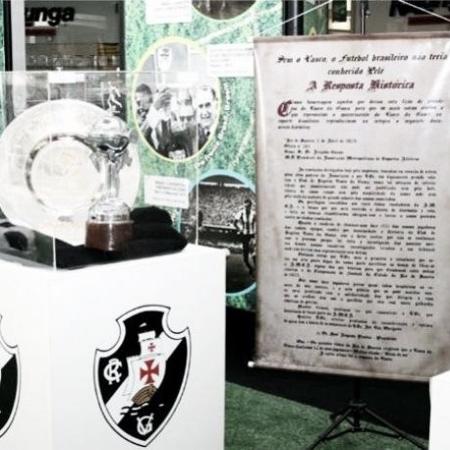 Banner da Resposta Histórica ao lado do troféu mais importante do Vasco: o da Libertadores de 98